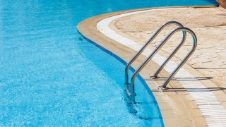 Una piscina sin bañistas permanece con el agua en calma.