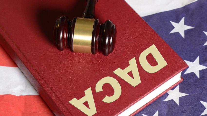 Foto de un libro que lee DACA con un mazo y la bandera de Estados Unidos.