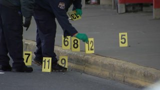 A Philadelphia police officer sets down evidence markers at the site of a shooting.