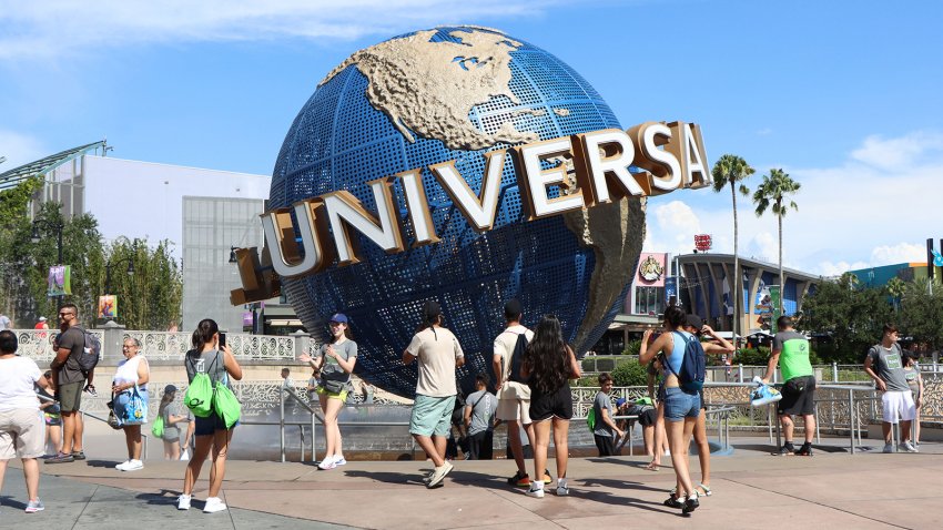 Tourists take photos at the globe outside the entrance to Universal Studios Orlando on Thursday, July 21, 2022. (Katie Rice/Orlando Sentinel/Tribune News Service via Getty Images)