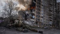 Un agente de la policía de Ucrania se pone a cubierto frente a un edificio en llamas, en Avdiivka, Ucrania, el 17 de marzo de 2023. El segundo año de lucha contra la invasión de Rusia no ha dado tregua ni los soldados ni a la población civil de Ucrania. Los fotógrafos de The Associated Press documentaron los 12 últimos meses de muerte y destrucción, de agonía y dolor — además de los atisbos de alegría — que marcan la vida durante una guerra. (AP Foto/Evgeniy Maloletka)