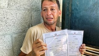 Mohamed Abu Al-Qomasan llora mientras sostiene los cettificados de nacimiento de sus hijos, en Deir Al-Balah, Gaza, el martes.