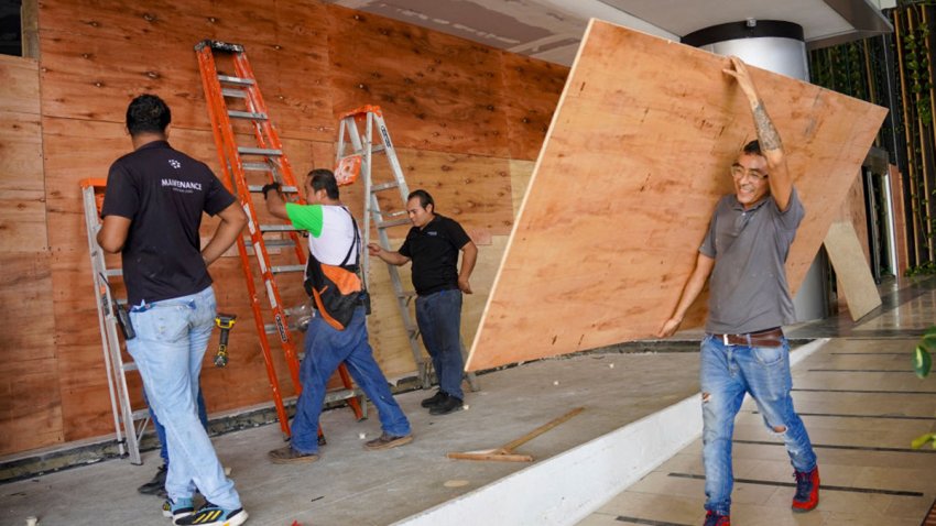 Workers place sheets of wood over windows and glass doors to protect them from the strong winds expected with the arrival of Hurricane Milton in the hotel zone of Cancun, Quintana Roo State, Mexico, on October 7, 2024. Hurricane Milton exploded in strength Monday to become a potentially catastrophic Category 5 storm bound for Florida, threatening the US state with a second ferocious storm in as many weeks. Milton, which is also forecast to graze Mexico’s Yucatan peninsula as it churns eastward, rapidly intensified to the highest category on a scale of five, triggering evacuation orders and alarms about a life-threatening storm surge in major population centers, including Tampa Bay. (Photo by Elizabeth RUIZ / AFP) (Photo by ELIZABETH RUIZ/AFP via Getty Images)