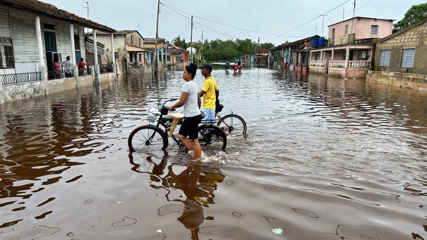 TOPSHOT – People wade through a flooded street after the passage of Hurricane Rafel in Batabano, Mayabeque province, Cuba, on November 7, 2024. Hurricane Rafael knocked out power to all of Cuba on Wednesday as it slammed through the cash-strapped island, which was still reeling from a recent blackout and a previous deadly storm. Rafael strengthened to a major Category 3 hurricane as it made landfall on the Caribbean island of 10 million people. (Photo by Yamil LAGE / AFP) (Photo by YAMIL LAGE/AFP via Getty Images)