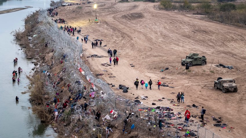 Visto desde una vista aérea, inmigrantes caminan hacia un centro de tránsito de la Patrulla Fronteriza de Estados Unidos después de vadear el Río Grande desde México a primera hora del 20 de diciembre de 2023 en Eagle Pass, Texas.