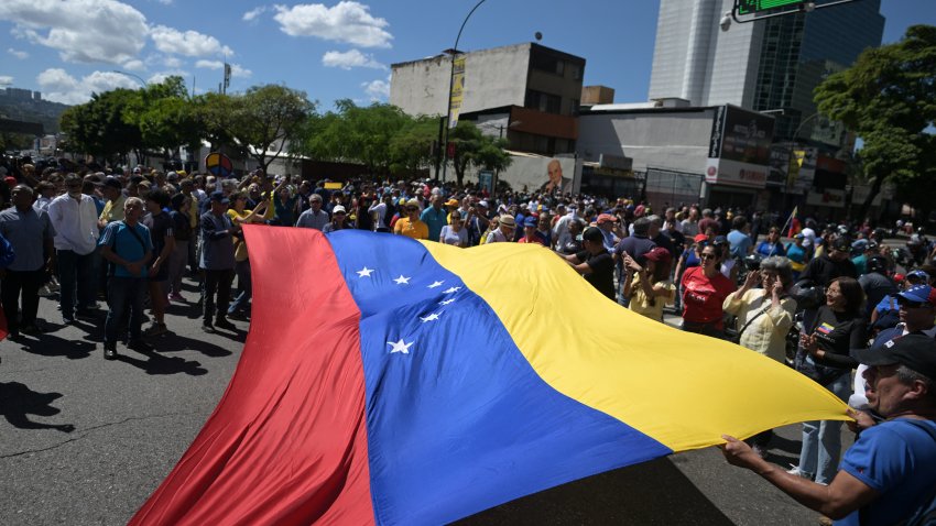 Demonstrators unfold a huge Venezuelan flag during a protest called by the opposition on the eve of the presidential inauguration in Caracas on January 9, 2025. Venezuela is on tenterhooks facing demonstrations called by both the opposition and government supporters a day before President Nicolas Maduro is due to be sworn in for a third consecutive term and despite multiple countries recognizing opposition rival Edmundo Gonzalez Urrutia as the legitimate president-elect following elections past July. (Photo by JUAN BARRETO / AFP) (Photo by JUAN BARRETO/AFP via Getty Images)