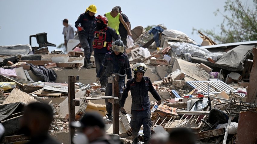 Rescue workers walk across the rubble of collapsed buildings during search efforts following an earthquake in Venezuela
